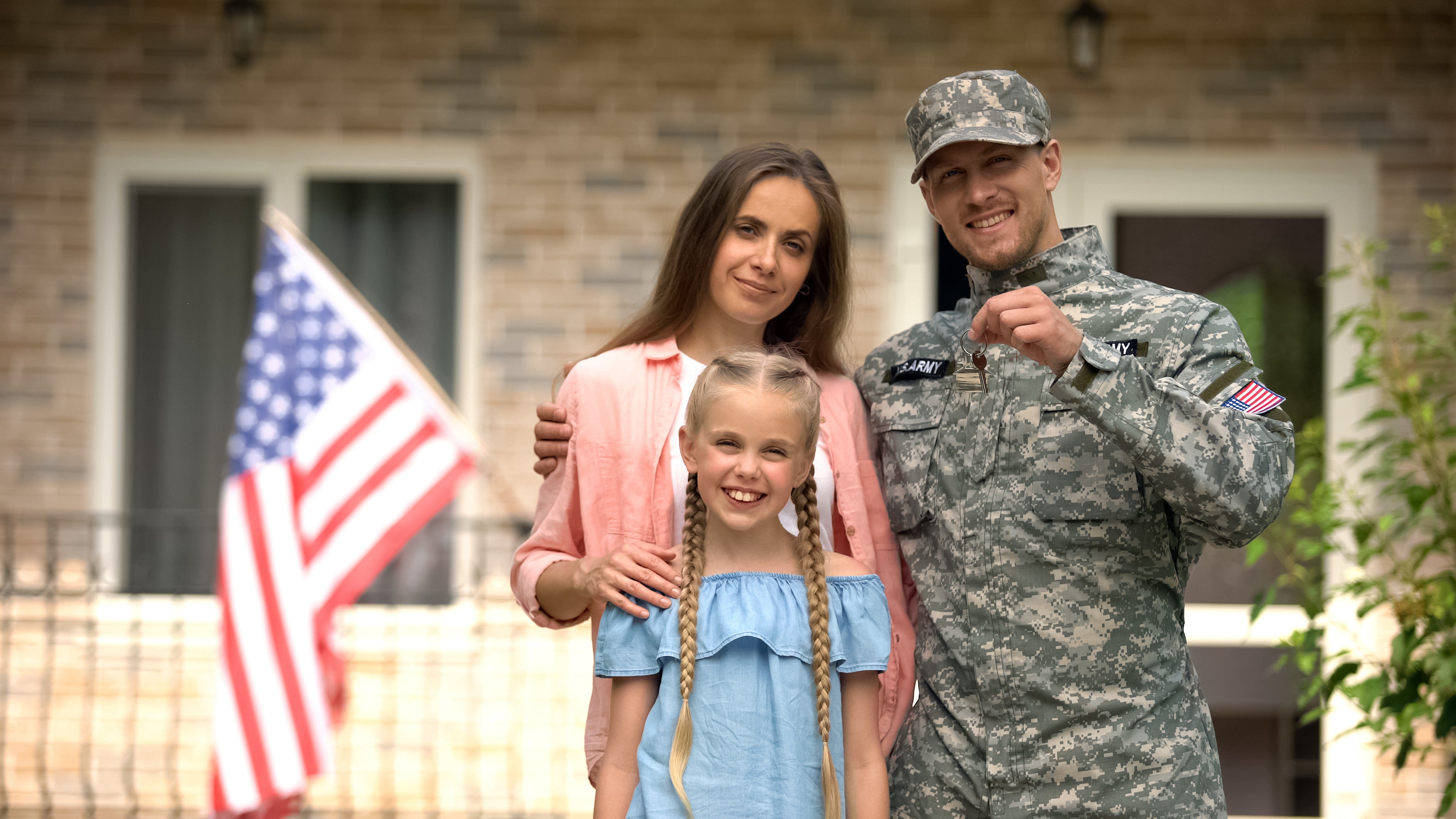 a family standing in front of a house with an american flag