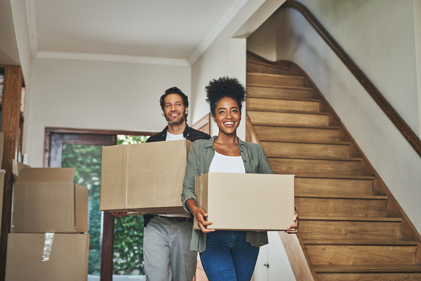 A man and woman move boxes into their new home.
