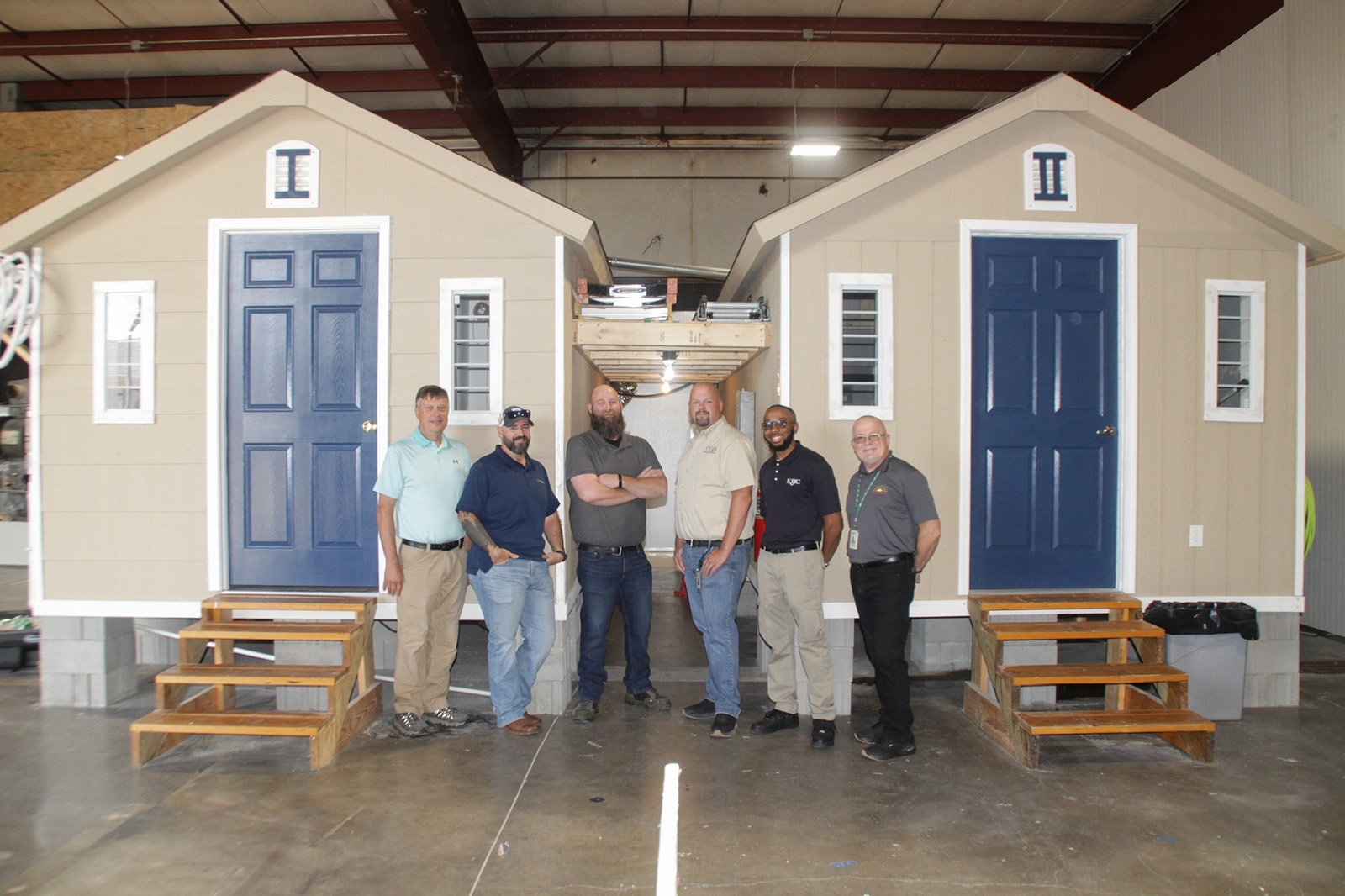 A group of men standing in front of tiny homes.